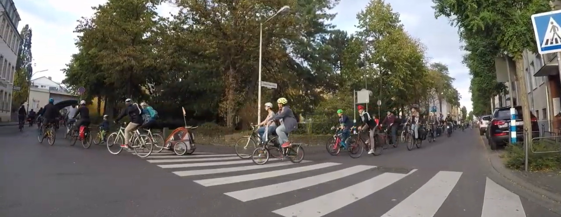 Eine lange Reihe Fahrradfahrende fahren über eine Kreuzung