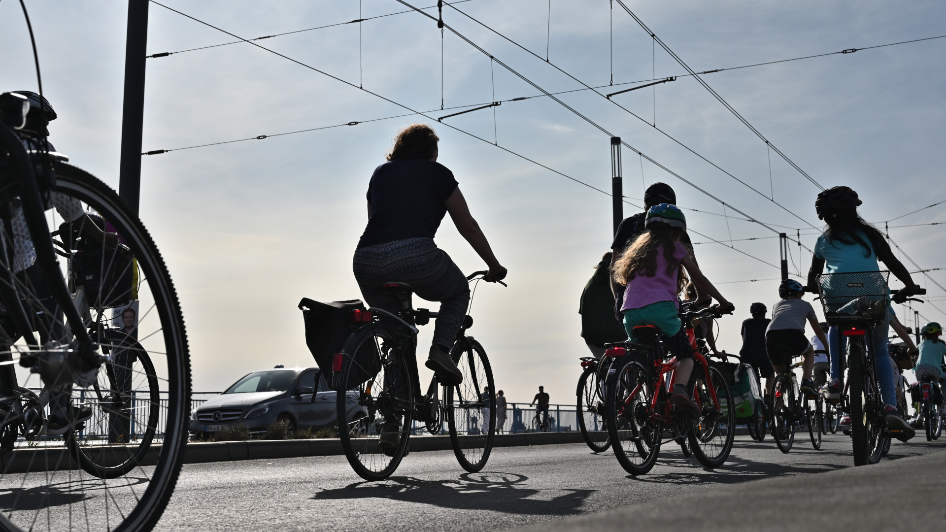 Große und kleine Radfahrer:innen fahren über die Kennedybrücke